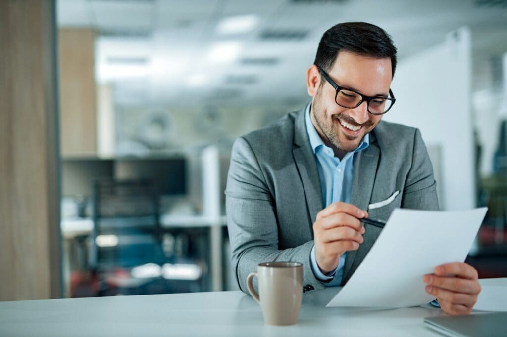 Happy businessman in office looking at document, portrait.